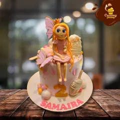 A sweet fairy-themed cake for a second birthday. This design features a hand-sculpted fairy with butterfly wings sitting atop a pink cake, decorated with mini cakesicles and the name Samaira.