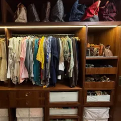 The 'Her' side of the closet features space for dresses and tops, with dedicated shelving for a handbag collection. We used matching bins to store smaller items and maintain a cohesive look.