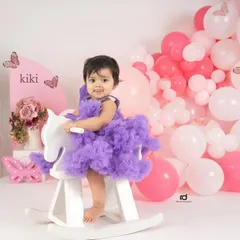 Dressed in a fluffy purple tutu, this birthday girl looks adorable on her white rocking horse. It's a sweet and playful portrait to mark her first year.