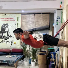 A student holds a challenging pose suspended by wall ropes. This builds immense core strength, back strength, and body awareness.