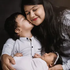 A heartwarming portrait of a mother with her two children. The older brother’s sweet kiss and the peaceful newborn create a beautiful image of growing family love.
