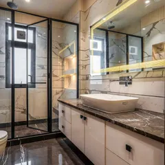 This modern bathroom is all about clean lines and a touch of sophistication. The combination of white marble-patterned walls, a dark marble countertop, and a large backlit mirror creates an experience of everyday luxury.