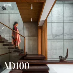 A view of the Bansal Residence, an AD100 project from 2020. The space is defined by the interplay of raw concrete and warm wood, with a floating staircase creating a sense of lightness and movement.