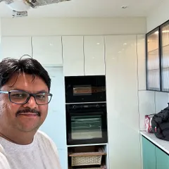 Here I am on-site with a nearly finished kitchen. This design includes a tall unit with a built-in oven and microwave, along with pull-out wicker baskets for vegetable storage.