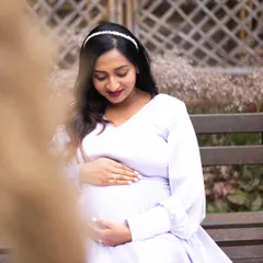 A serene solo portrait of an expecting mother gently holding her baby bump. The soft, natural lighting and her peaceful expression perfectly capture the quiet anticipation of motherhood.