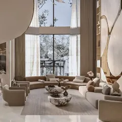 This angle captures the impressive floor-to-ceiling windows that flood the reception area with natural light. The curved sectional sofa follows the organic lines of the space, enhancing the feeling of openness and connection to the outdoors.