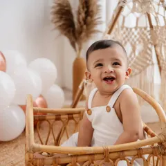 Such a happy boy in my boho studio! This little one is sitting in a wicker basket, surrounded by balloons and a teepee, celebrating his first birthday in style.