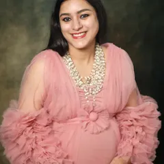 A beautiful close-up of a smiling mom-to-be in a frilly pink gown. Her happy expression and the soft texture of the dress create a joyful and feminine portrait.