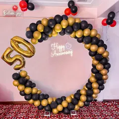 Celebrating 50 golden years together! A chic and modern circular balloon arch in black and gold, with large '50' foil balloons and a 'Happy Anniversary' neon sign, marks this incredible milestone in style.