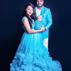 A full-length family portrait where the parents' coordinated blue outfits complement the baby's swaddle. This shows how we can style the entire family for a cohesive and beautiful photo.