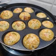 Freshly made puddu, also known as appe, cooking in a special pan. These savory rice balls are a popular South Indian snack.