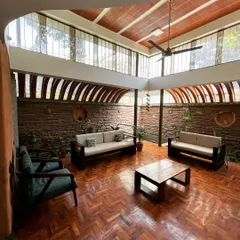 Is it a living room or a room with life? This space is defined by light. Large windows and a vaulted ceiling with exposed clay tubes create an airy, open atmosphere, while the brick wall adds warmth and texture.