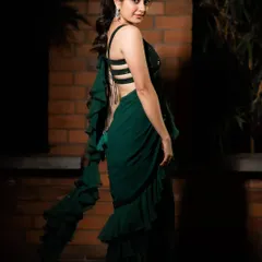 This emerald green saree gown is my modern take on a classic silhouette, designed for actress Ashika Ranganath. It combines the ease of a gown with the elegance of a saree, featuring cascading ruffles and a stylish strappy back for a contemporary cocktail look.
