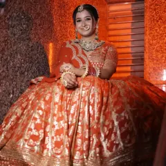 This close-up shot shows the rich gold foil work on this orange-red bridal lehenga, perfect for capturing stunning portraits.