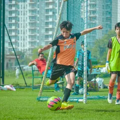 Here, a young footballer from our academy lines up a crucial shot on goal during the Pride Cup. We focus on creating opportunities for youth players to test their skills in real-match situations, building their confidence and love for the game.