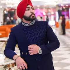 A client looking sharp in a custom navy blue Indo-Western jacket. The piece features an asymmetrical design with a textured, embellished panel and a decorated collar.