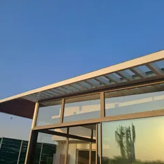 The clean lines of the steel and glass framework against a clear blue sky. This image captures the minimalist aesthetic and precision engineering of our prefabricated architectural additions.