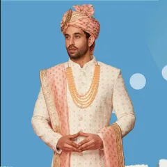 We believe every groom deserves to feel like royalty. This classic ivory sherwani with intricate embroidery, paired with a pastel pink safa and dupatta, is a timeless choice for a regal wedding look.