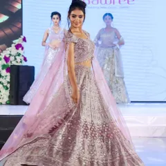 A smiling, confident moment on the runway. This shot captures the beauty of the lavender lehenga and the model's energy, creating a perfect image for event coverage and promotion.