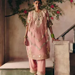 A beautiful moment on the stairs. This model wears a dusty pink kurta set with delicate gold embroidery, showcasing a look of timeless elegance.