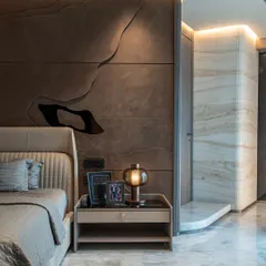 In this plush bedroom at Lodha World View, seamless marble cladding elegantly conceals structural columns, creating a fluid and uninterrupted aesthetic. This meticulous attention to detail transforms the bedroom into a tranquil retreat, where our mastery of precision craftsmanship radiates sophistication and calm.
