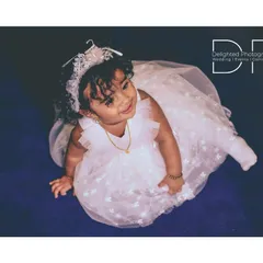 An angelic top-down shot of the birthday girl in her white party dress and tiara, looking up with a sweet expression.