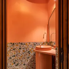 Even a small powder room can make a big statement. We designed this space with a custom concrete pedestal basin and vibrant pink walls, complemented by terrazzo flooring and brass fixtures. It’s a playful and unexpected moment of bold design.