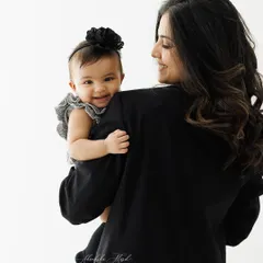 A modern and chic mother-daughter portrait. The mother's black blazer contrasts beautifully with her baby's happy smile, creating a stylish and timeless image.
