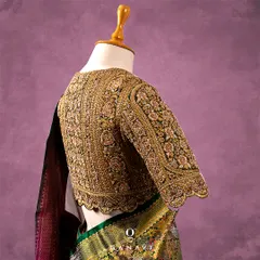 A back view of the heavily embroidered gold blouse, showing the seamless continuation of the intricate pattern. The scalloped hem adds a final touch of delicate craftsmanship to this statement piece.