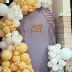 A close-up view of the balloon arrangement for the Umrah Mubarak celebration, showing the mix of different sized balloons in pastel yellow and white to create a soft, cloud-like effect.
