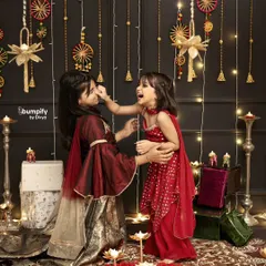 A playful, candid moment between sisters during their Diwali photoshoot. It's these unscripted interactions that truly capture the spirit of family and celebration.