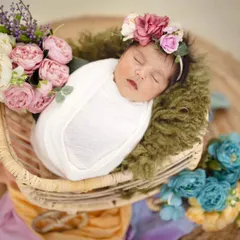 A sweet 22-day-old baby girl sleeping peacefully in a carry cart. The arrangement of soft flowers around her adds a dreamy, delicate touch to this newborn portrait.