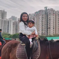 A mother securely holds her toddler during a gentle joy ride. These introductory experiences are perfect for creating a positive and memorable first interaction with horses.
