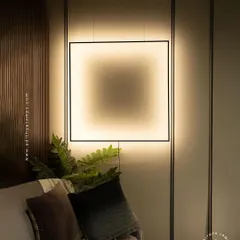 A true statement piece, this suspended square frame light is a unique alternative to a floor lamp. It hangs from the ceiling and is anchored to the floor, creating a floating frame of light that playfully illuminates the wall.