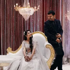 A romantic pose on a glamorous reception stage. The decor features a stunning crystal chandelier and a backdrop of shimmering bead curtains, creating a sophisticated and sparkling setting for the couple.