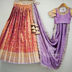 A deconstructed view of a half-saree set, featuring a red and orange brocade lehenga and a lavender embroidered blouse and dupatta.