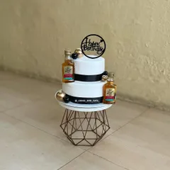 A sophisticated two-tier cake with mini liquor bottles, perfect for a man's birthday celebration. The black, white, and gold theme adds a touch of class.