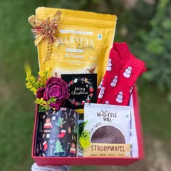Unboxing the magic of Christmas with this delightful hamper. It contains a Christmas-themed mug, crunchy vanilla biscuits, a stroopwafel, and a pair of festive snowman socks, making it a cozy and fun holiday present.