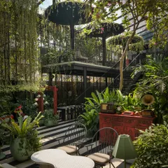 Here, vintage objects like a gramophone and a red cabinet are placed within the lush greenery, adding a layer of retro storytelling. This juxtaposition of curated objects and wild planting creates unique, explorable moments throughout the restaurant space.