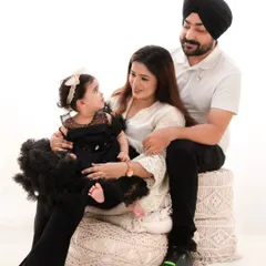 A stylish family portrait against a clean white background. The family's black and white attire creates a striking, high-contrast look that is both modern and timeless.