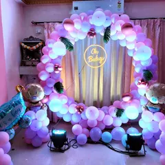 A lovely balloon ring backdrop for a baby shower in shades of purple and pink. The "Oh Baby" neon sign, along with foil balloons shaped like a baby carriage and bottle, makes the theme clear and cute.