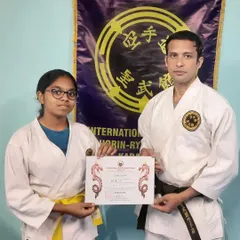 I present a certificate to a student, formally acknowledging her successful completion of her Kyu grading requirements. Each certificate is a testament to the effort and focus she has invested in her training.