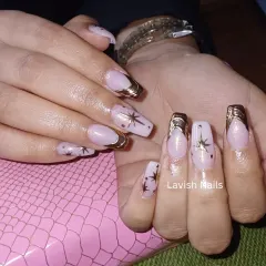 This celestial-themed French manicure features square-shaped nails with gold chrome tips and delicate, hand-painted starbursts. It's a unique design that adds a touch of magic to a classic style.