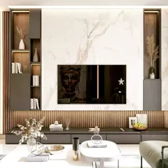 A modern living room centered around a custom media wall. This entertainment unit features a full-height marble backsplash, flanked by integrated wood-paneled shelving with internal lighting, creating a perfect balance of texture and luxury.