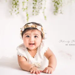 A pure bundle of joy during her sitter session. The simple white backdrop and hanging greenery put all the focus on her adorable expression and bright eyes.