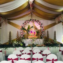 A wider view of the seating arrangement for the Ganesh Chaturthi festival. The chairs are adorned with red sashes, and the tent ceiling is draped with flowing fabric, creating a festive and cohesive look.