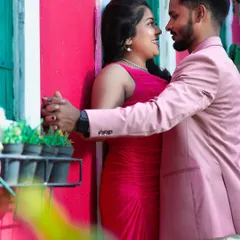 A romantic moment captured. The colours of their outfits pop against the bright background, creating a vibrant and happy picture.