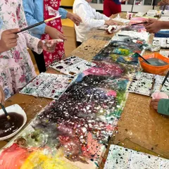A close-up of a collaborative galaxy painting. Children worked together, splattering and mixing colors to create this beautiful, cosmic masterpiece on a long table canvas.