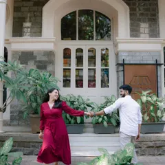A couple holds hands in front of a charming building with large white doors, sharing a look. This shot combines classic architecture with modern romance for a timeless urban portrait.