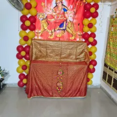 A simple decoration for a 'Mata ki Chowki' or Navratri puja at home. A red and yellow balloon frame surrounds the goddess's poster and the decorated table.